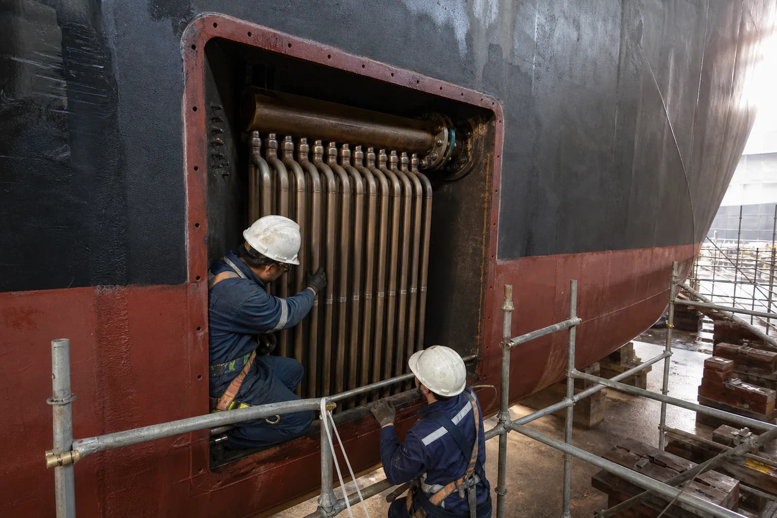 Marine technicians inspecting a box cooler tube bank inside a vessel sea chest in dry dock