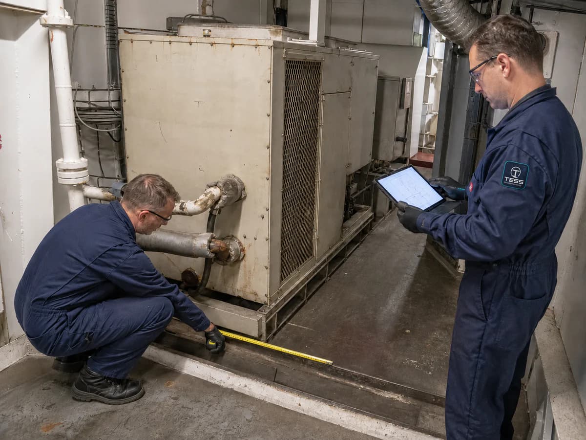 Marine engineers measuring the footprint and interfaces of an obsolete unbranded HVAC unit aboard a vessel